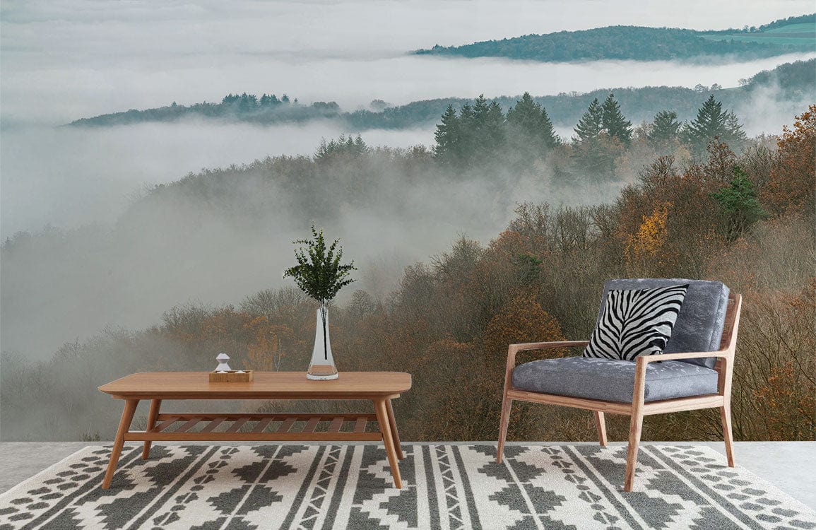 Misty Autumn Forest Mural Wallpaper in living room; features grey armchair, wooden table, patterned rug.