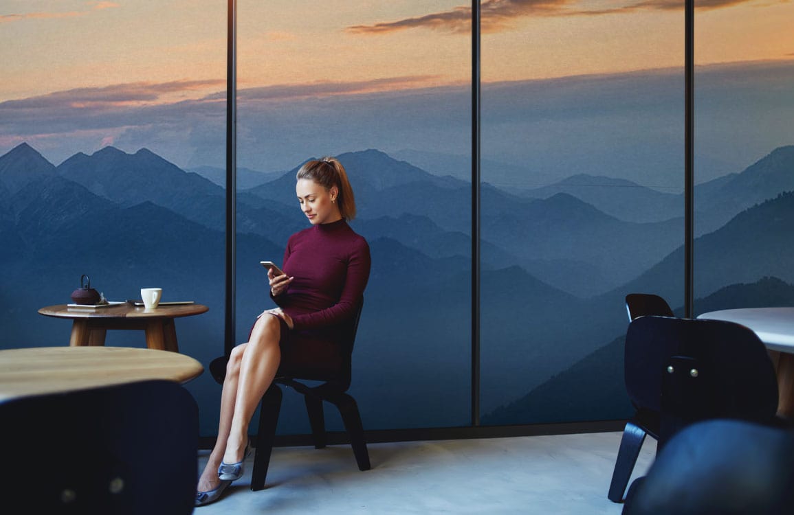 Tranquil Mountain Mist Mural Wallpaper, blue gradient; cafe setting with minimalist furniture, wooden flooring.