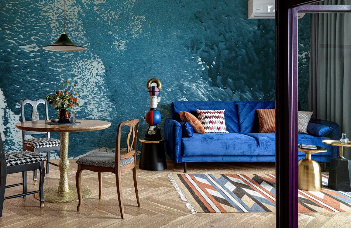 Teal ocean abstract mural wallpaper, modern living room, blue sofa, wooden flooring, dining table set.