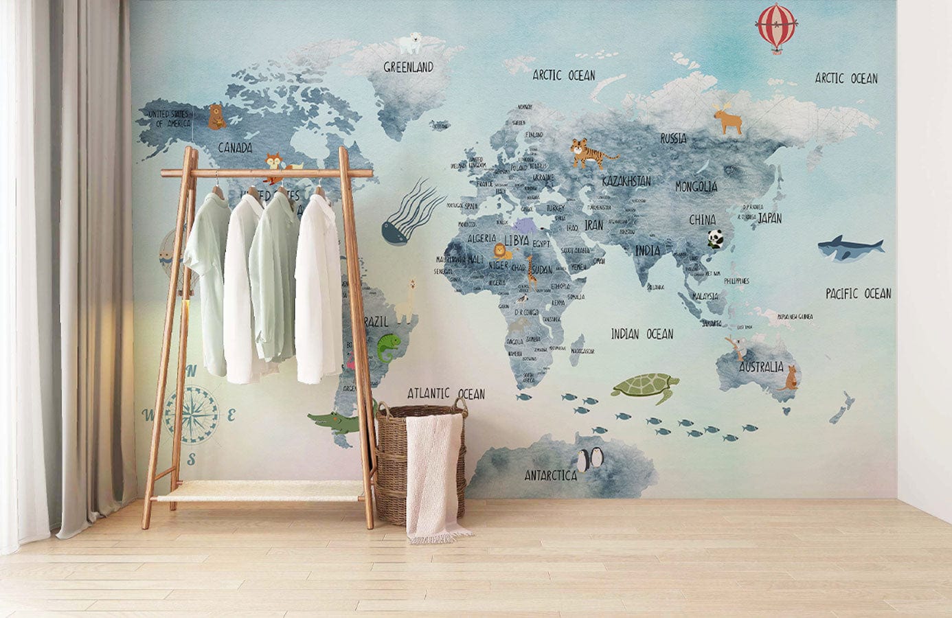 Whimsical World Map Mural Wallpaper in vintage blue tones, wooden clothing rack, light wooden flooring.