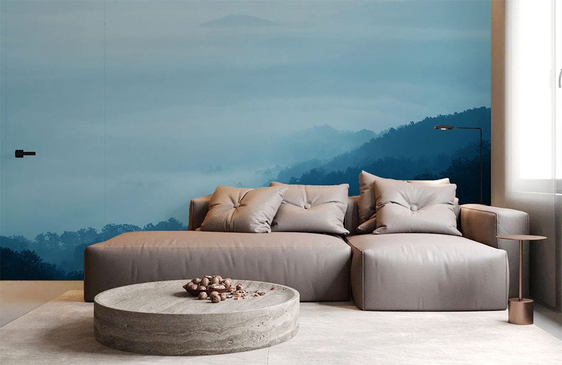 Tranquil Blue Mist Mountain Landscape Mural Wallpaper in living room with grey sofa and stone table.