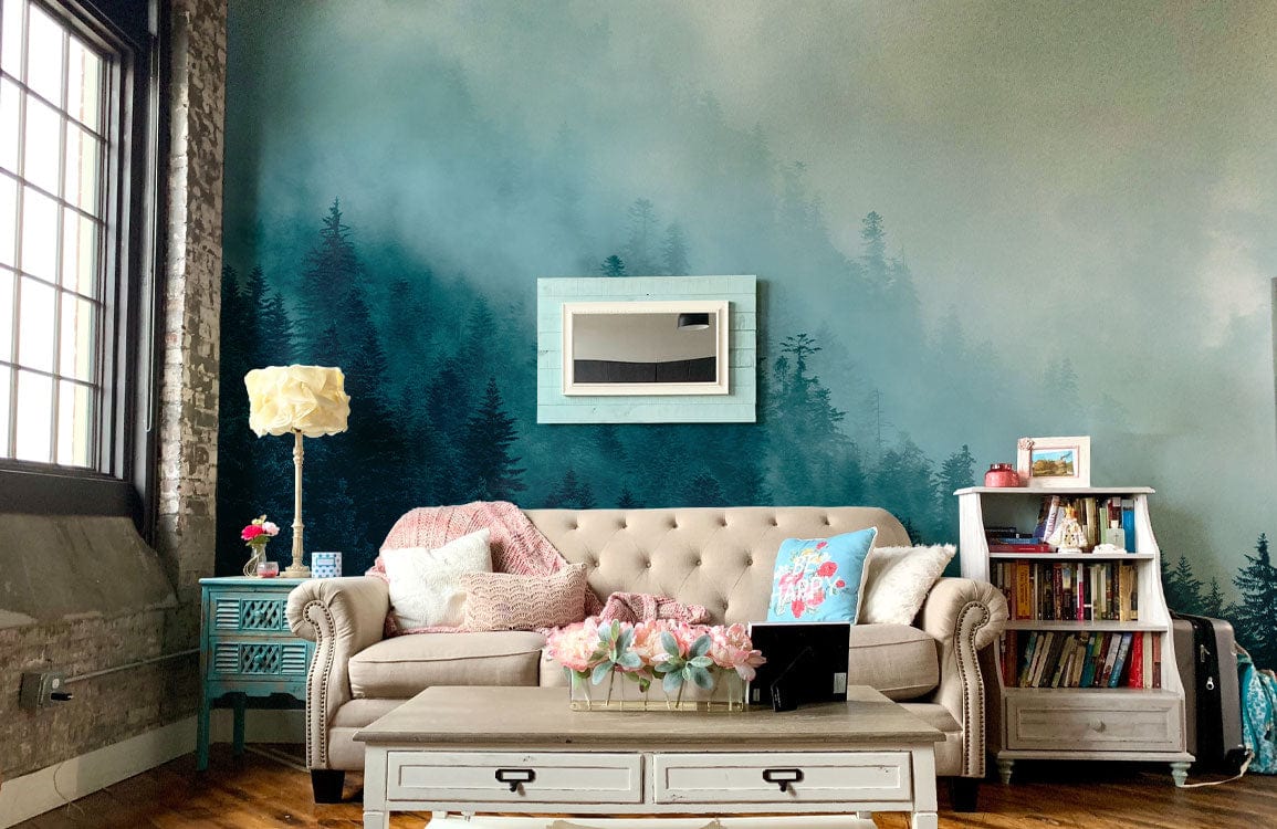Serene Misty Forest Mural Wallpaper; teal-grey tones; loft-style with tan sofa, rustic flooring, framed art.