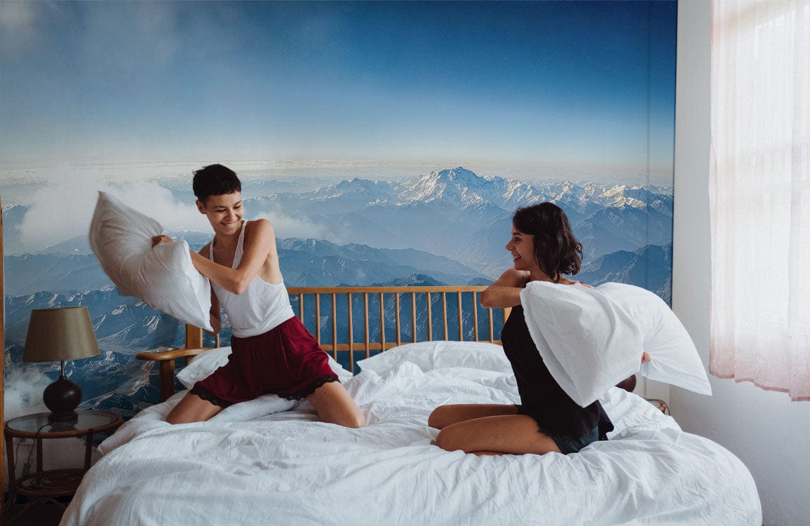 Panoramic Mountain Vista Mural Wallpaper in bedroom, with wooden bed frame and crisp white bedding.