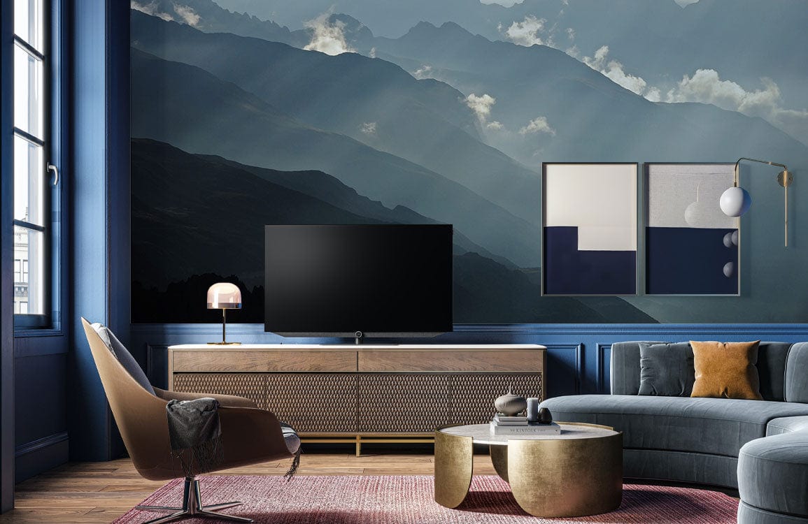 Luxury living room featuring Serene Mountain Landscape Mural in moody blue tones, modern sofa, and decor.