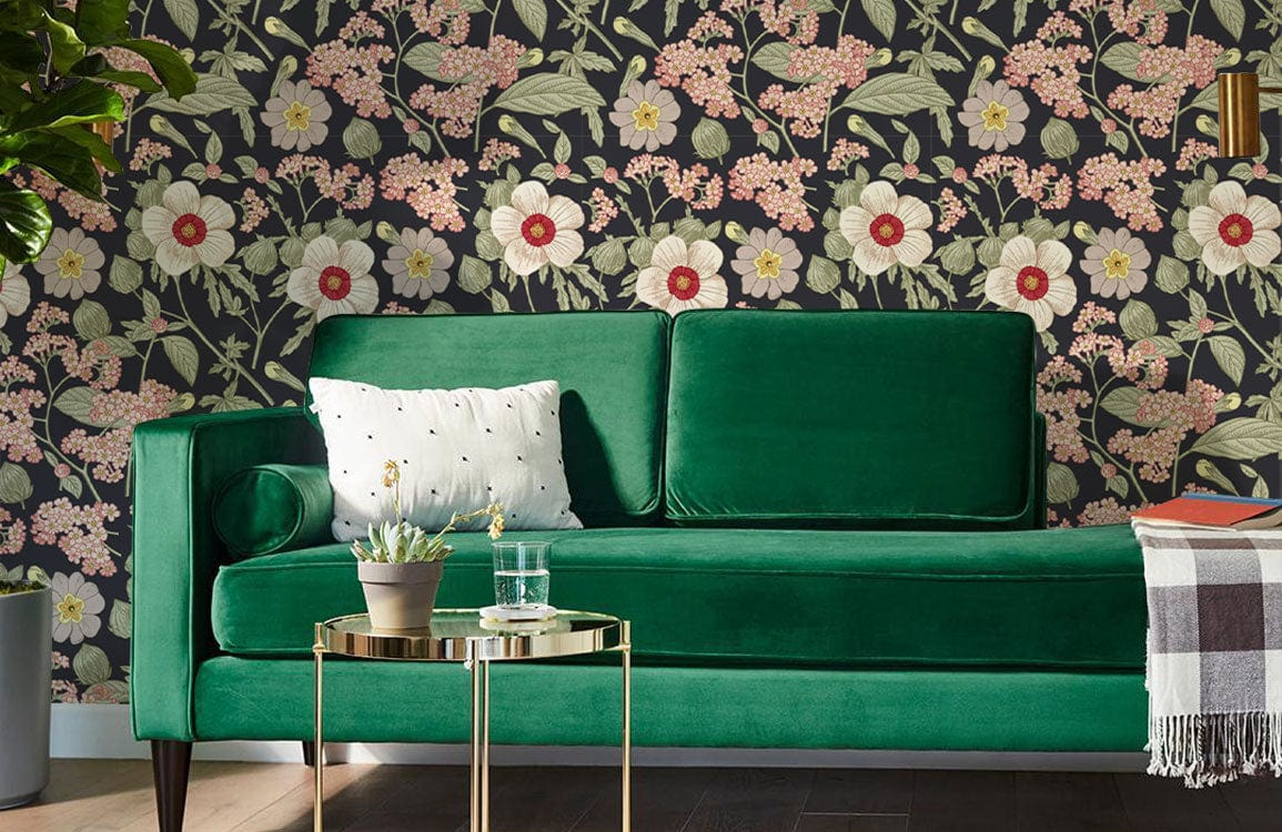 Vintage floral wallpaper in pink and green tones, green velvet sofa, wooden flooring, living room setting.