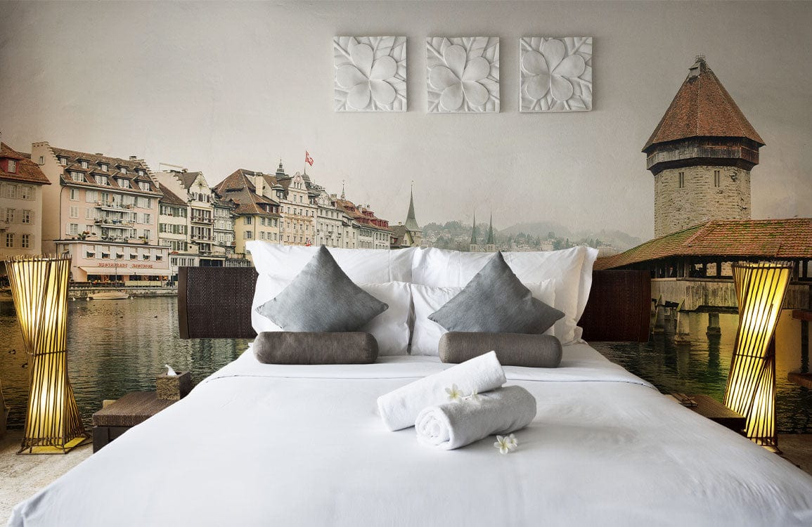 Bedroom with vintage lakeside architecture mural wallpaper in neutrals, white bedding, modern lamps and decor.