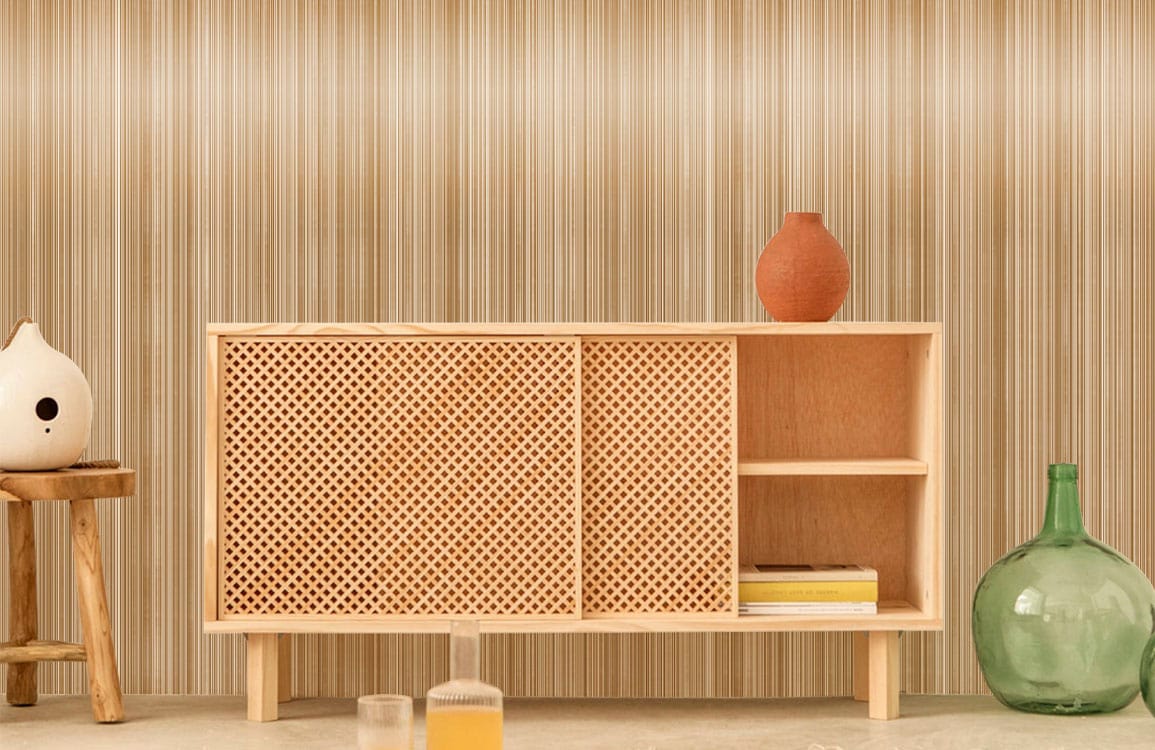 Modern wooden sideboard against striped wall with beige tones, featuring mid-century stool and glass decor.