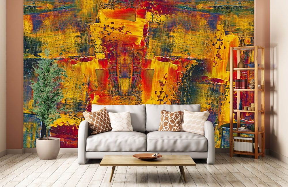 Vibrant abstract mural wallpaper, rich reds and golds; grey sofa, wooden flooring, modern living room.