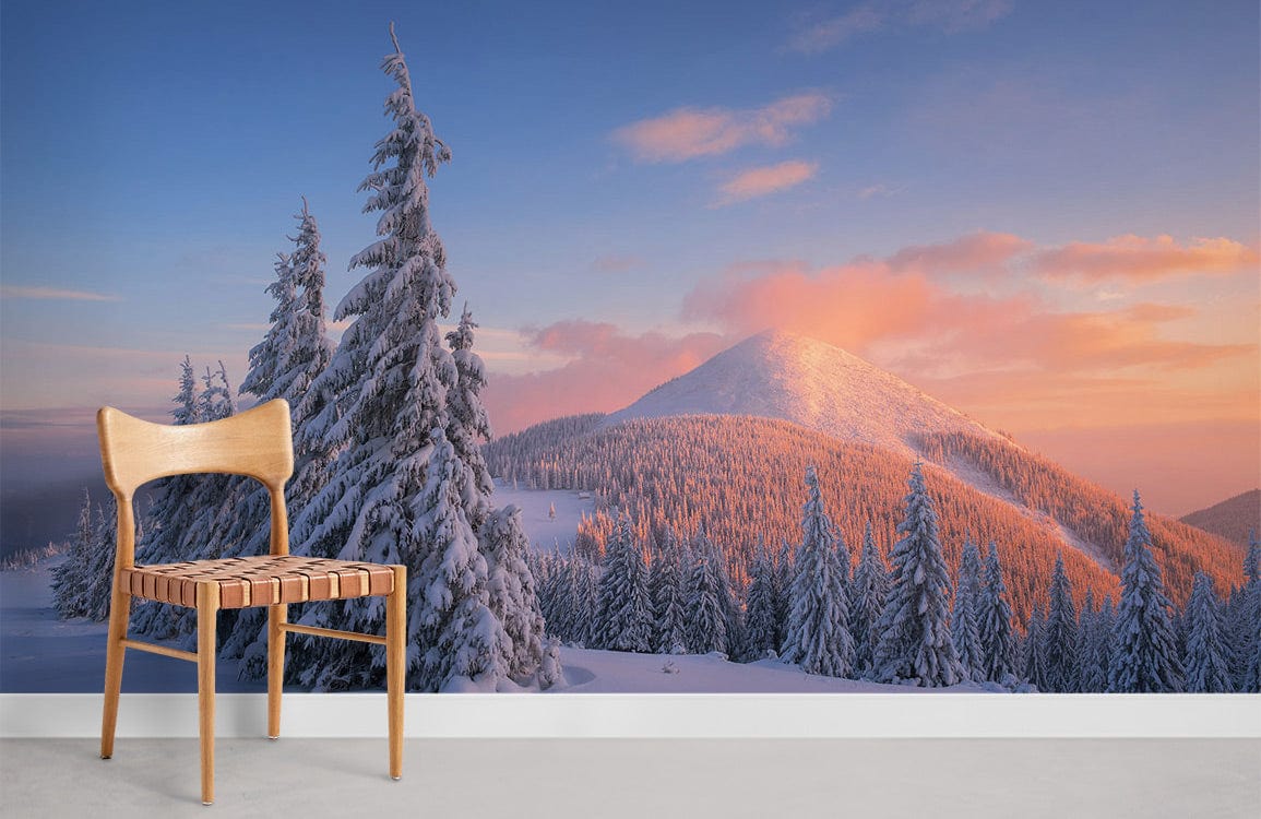 Winter Wonderland Mountain Landscape Mural Wallpaper with Snowy Pines, sunset glow; wooden chair, grey flooring.