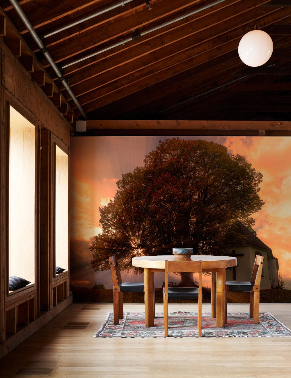 Tranquil Sunset Church Mural Wallpaper Autumn Scene, dining room setting, wooden table, vibrant rug, oak flooring.