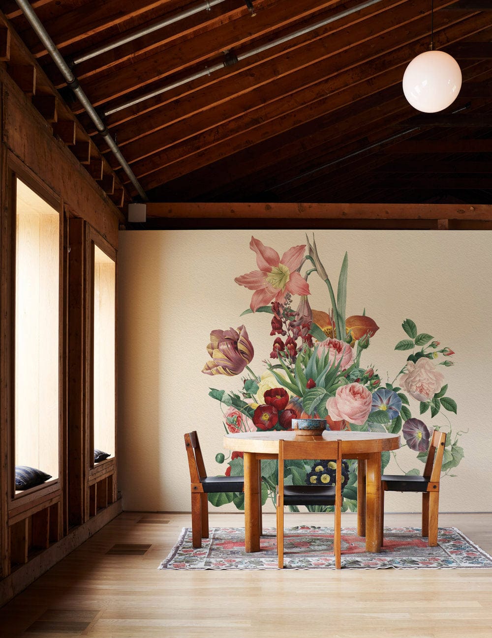 Vintage botanical mural wallpaper with pastel blooms in dining room; wooden table, chairs, wooden floor.