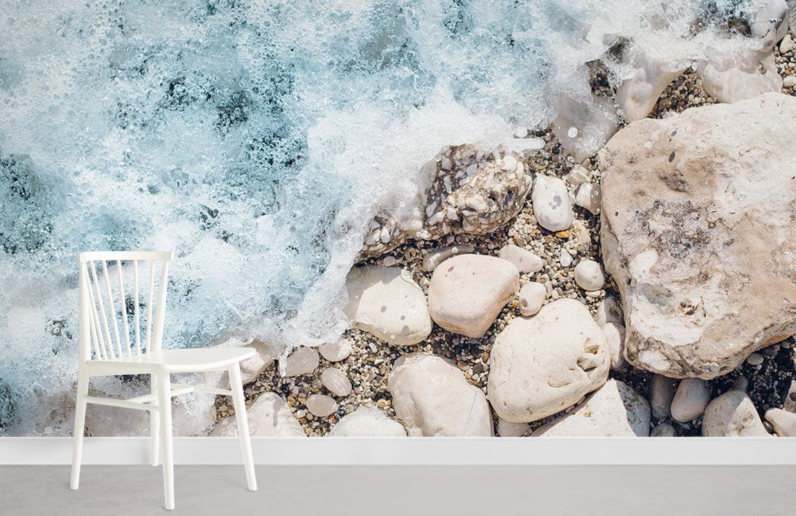 Coastal Serenity mural wallpaper with ocean foam, pebbles; white chair, grey flooring, modern Décor.