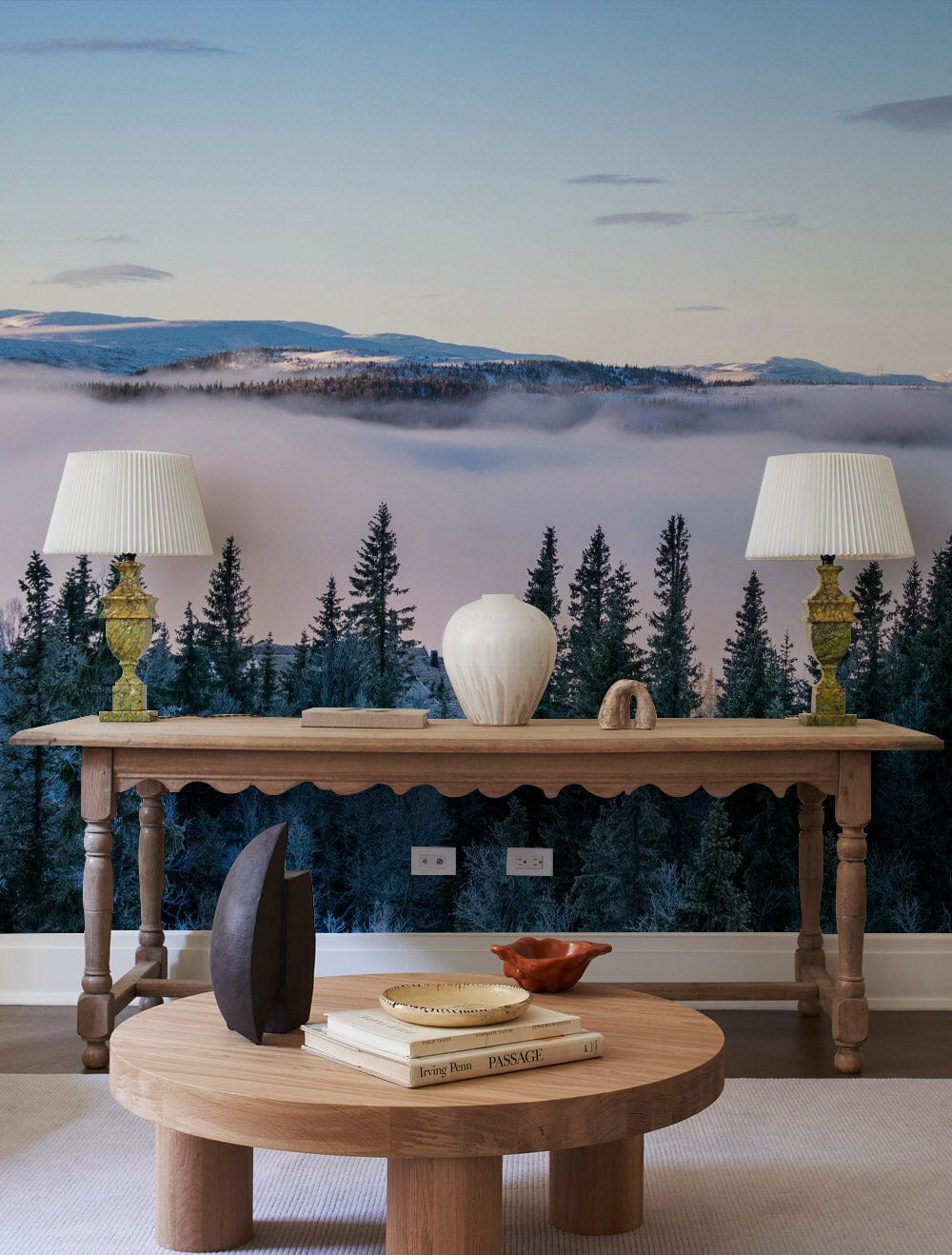 Mist-covered forest mural wallpaper, pinewood console table, decorative vase, lamp pair, round coffee table.
