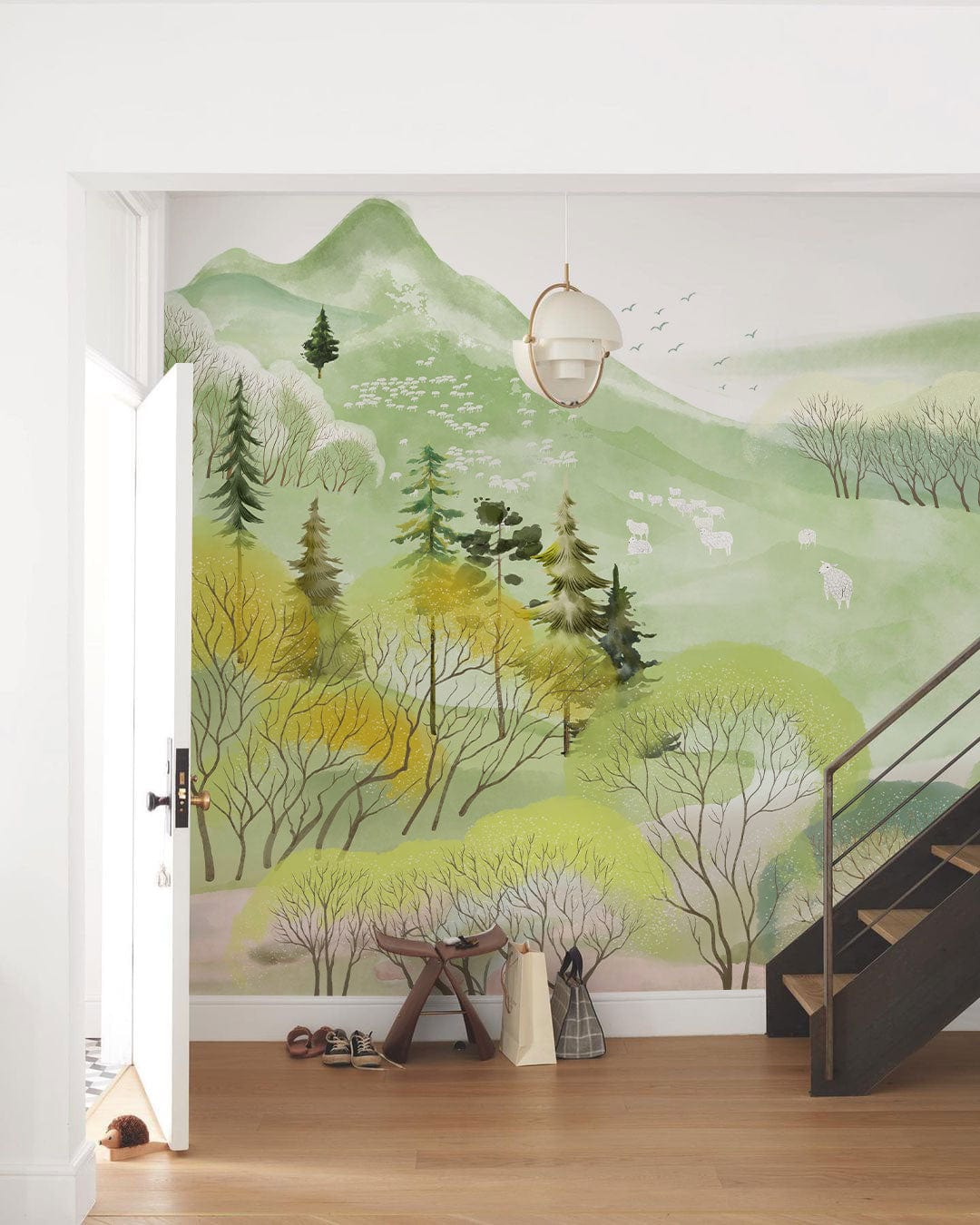 Serene Pastel Forest Landscape Mural Wallpaper in hallway with wooden staircase and pendant light.
