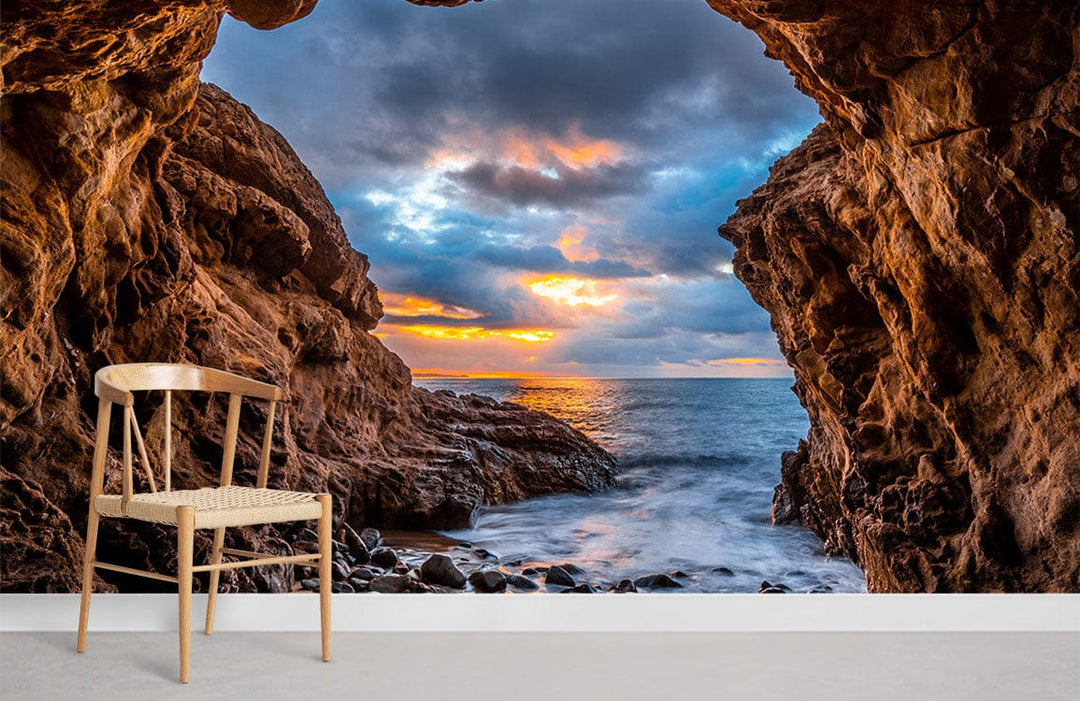 Stunning Ocean Cave Sunset Mural Wallpaper, vibrant coastal colours, wooden chair, minimalist style room.