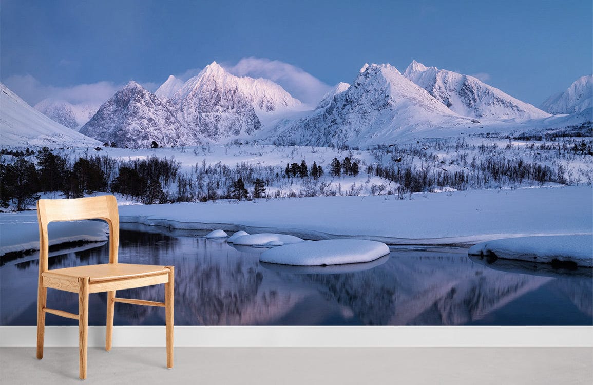 Serene snowy mountain mural wallpaper in blue tones, featuring a wooden chair on grey flooring.