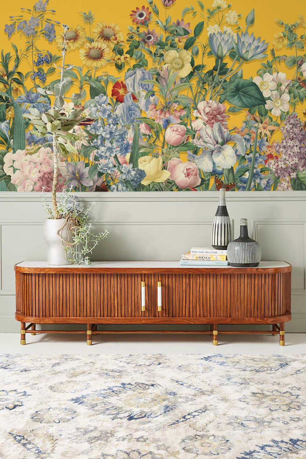 Yellow floral mural wallpaper, wooden cabinet, soft grey wall, elegant rug in stylish lounge setting.