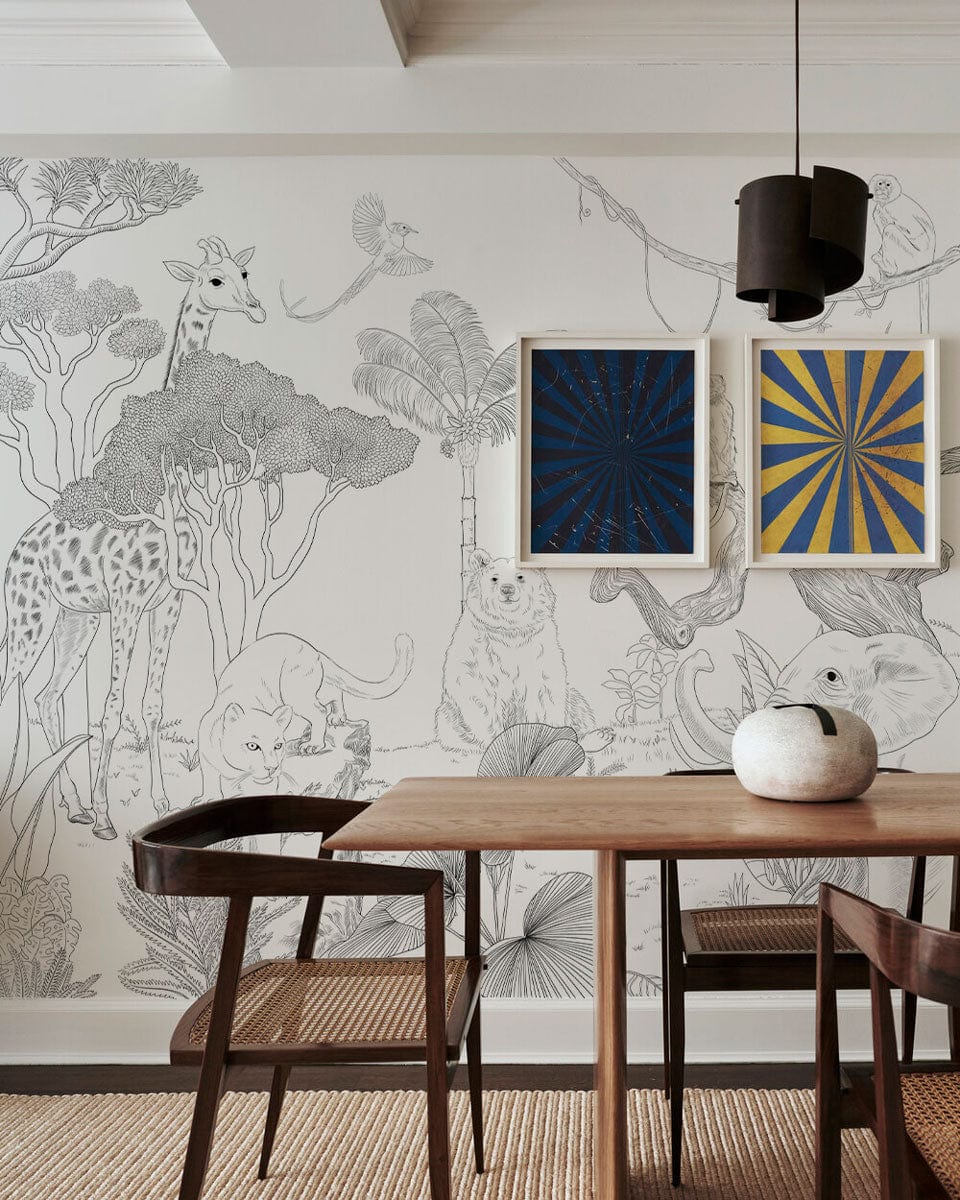 Monochrome Safari Wildlife Mural Wallpaper in dining room with wooden table, chairs, and artistic wall decor.