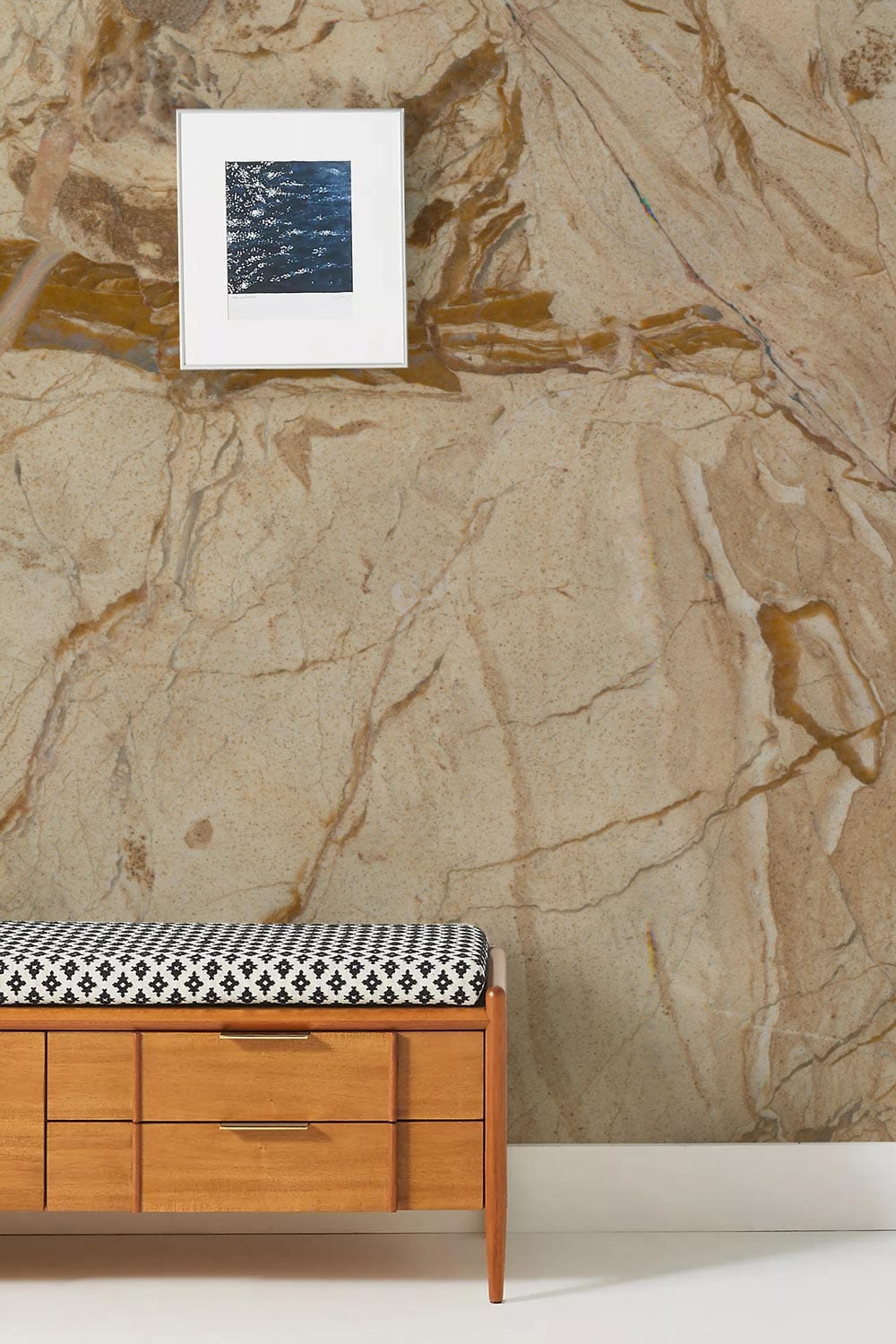 Gold marble mural with mid-century bench and framed art, perfect for modern interior design elegance.