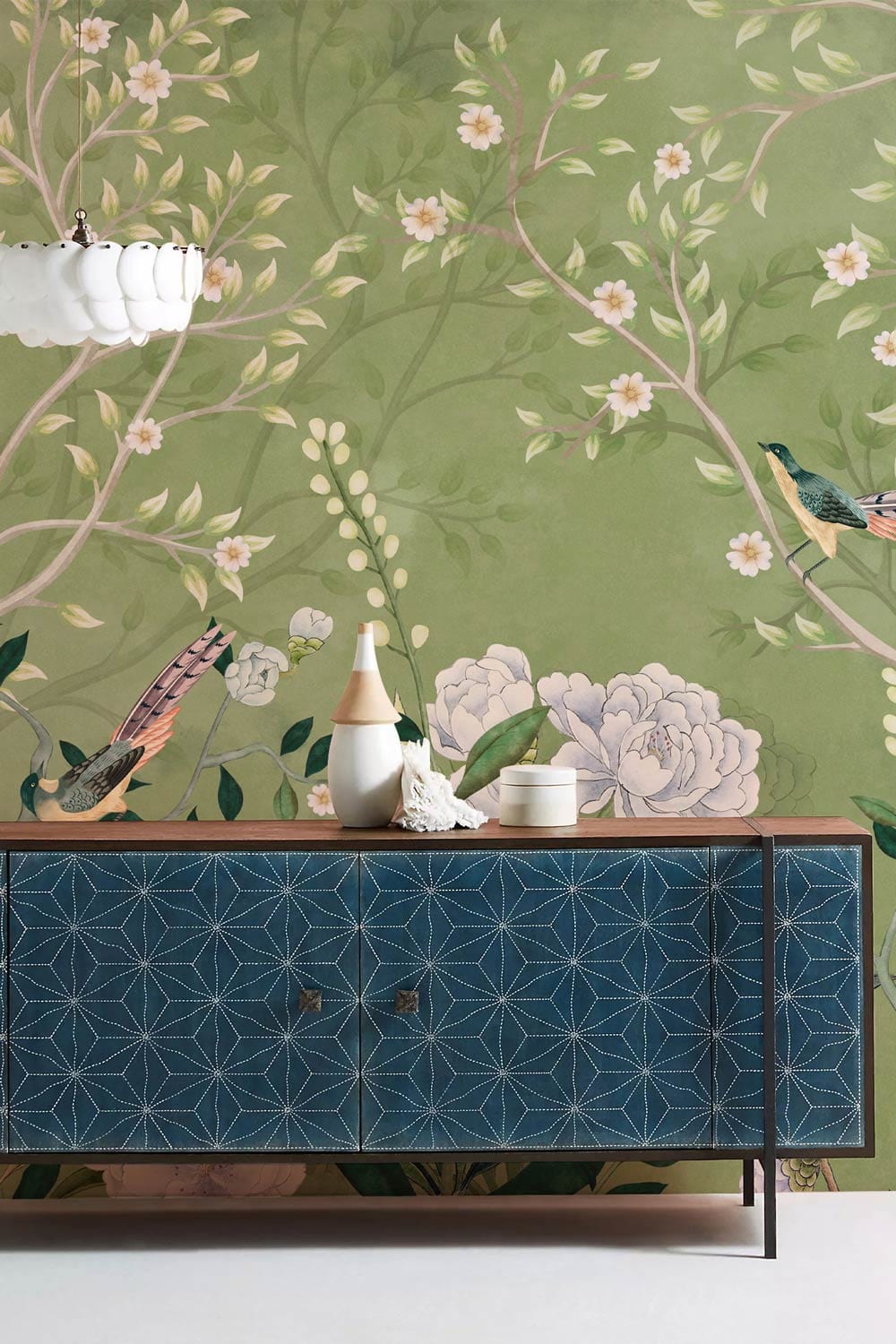 Elegant green floral bird mural wallpaper with blue geometric cabinet in traditional interior design.