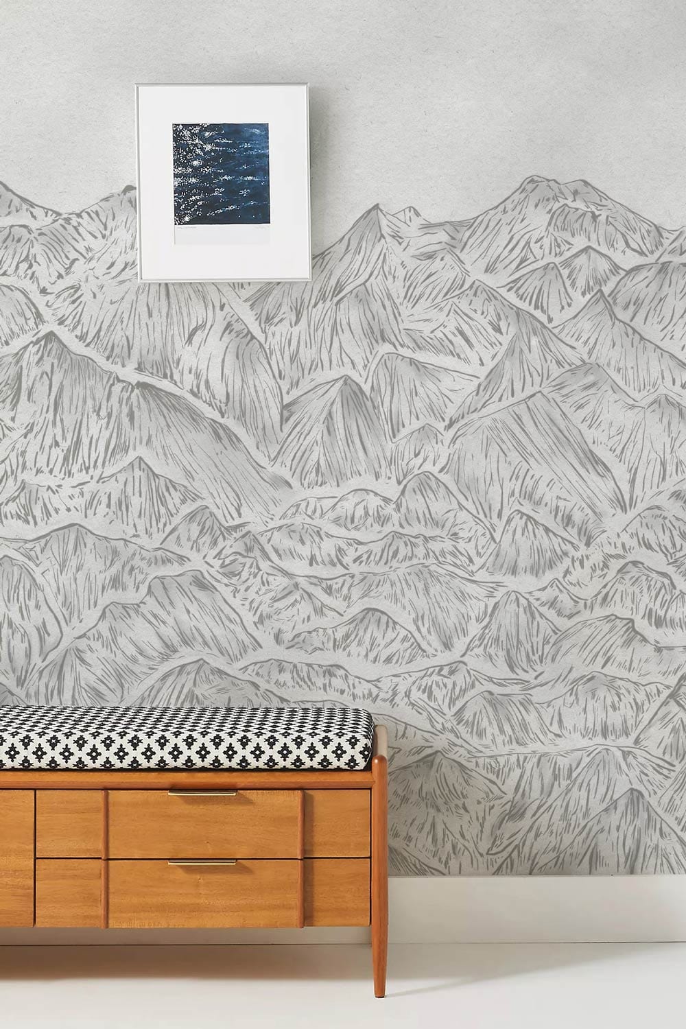 Grey Mountain Sketch Wallpaper Mural in room with mid-century wooden bench, neutral wall, framed artwork.