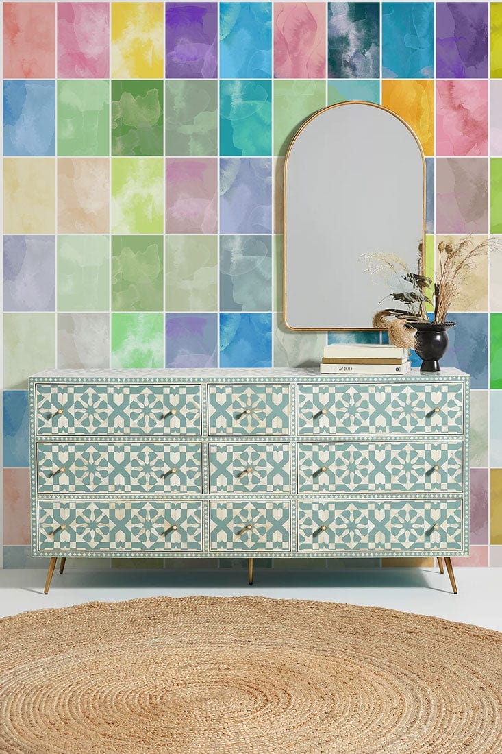 Vibrant mosaic wall mural with patterned sideboard, round jute rug, arched mirror in contemporary room.