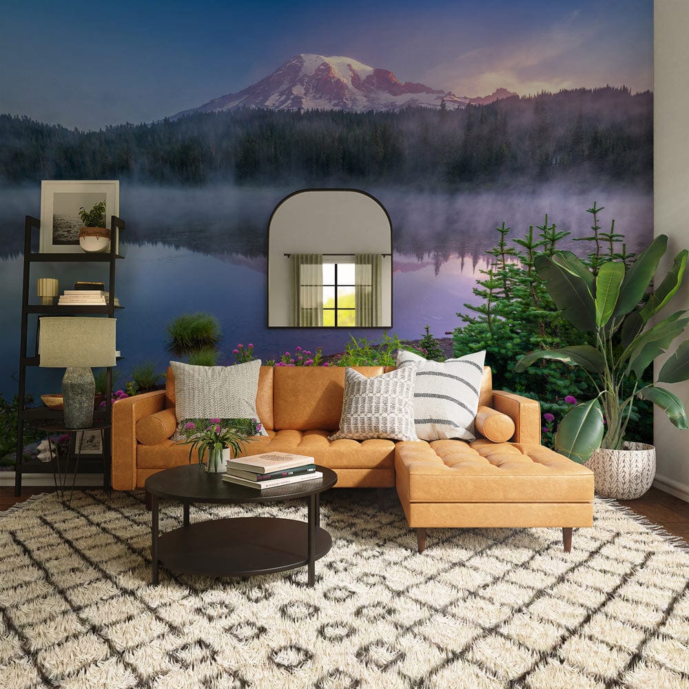 Tranquil mountain lake wallpaper mural with orange sofa, geometric rug, mirror, and dark wood flooring.