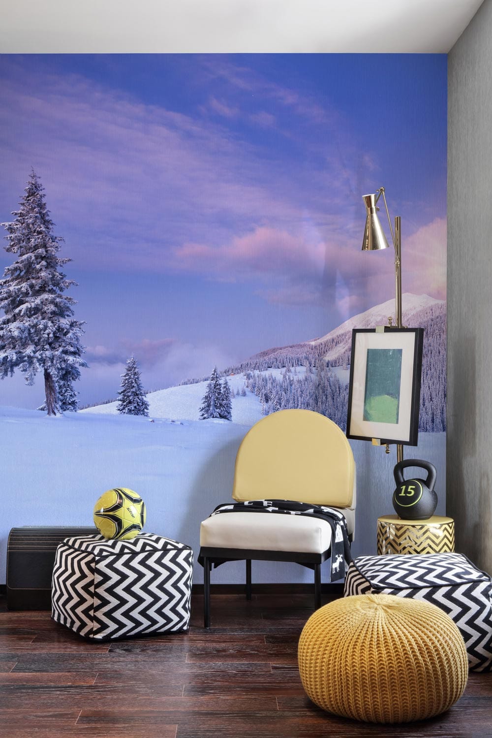 Tranquil Winter Dawn Mural in sitting room; yellow armchair, chevron poufs, wooden flooring, modern decor.