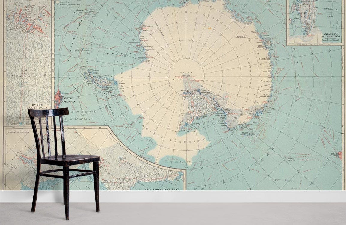 Vintage Antarctic Exploration Map Mural Wallpaper in blue with black chair; elegant, historical wall design.