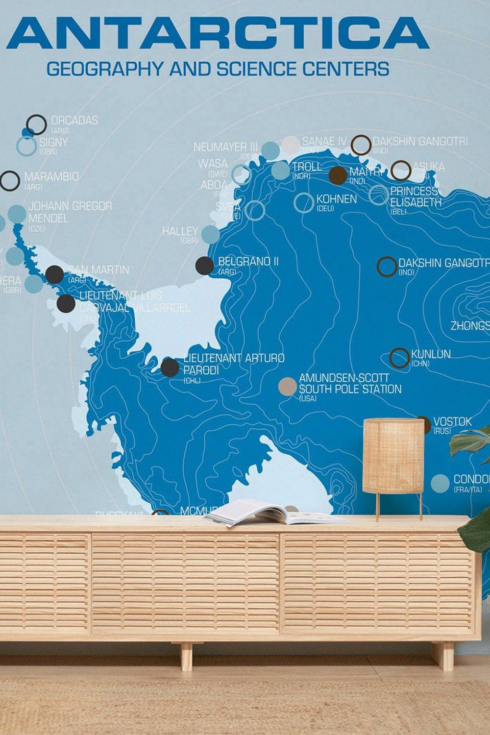 Elegant blue Antarctic map mural wallpaper in living room with wooden sideboard and modern lamp.