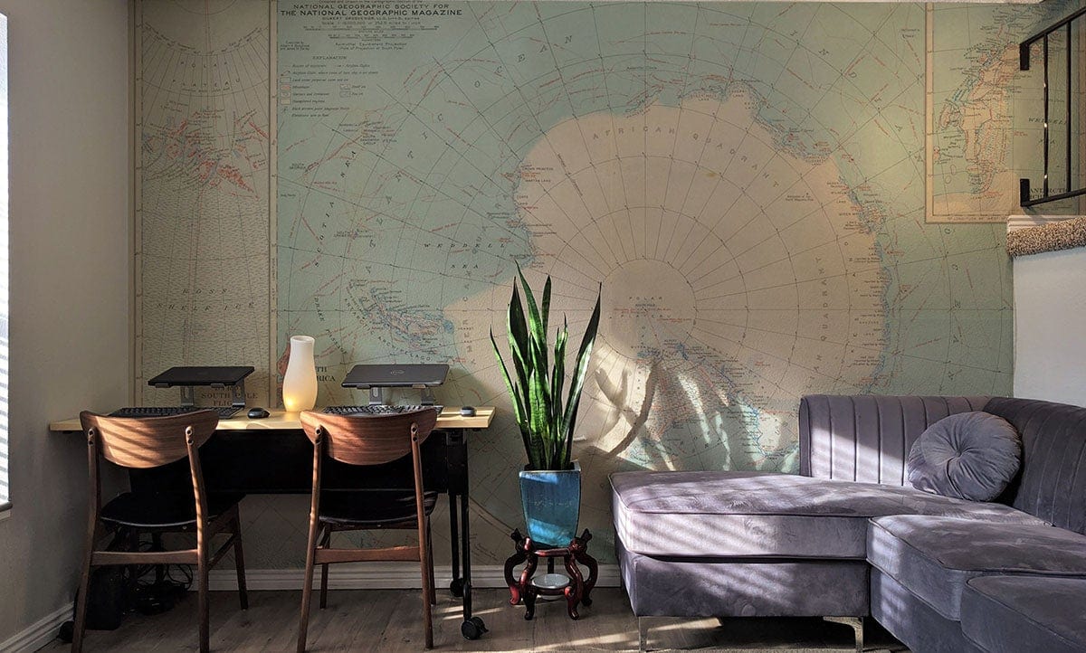 Vintage Antarctic map mural wallpaper in a stylish room with modern grey sofa and wooden desk.