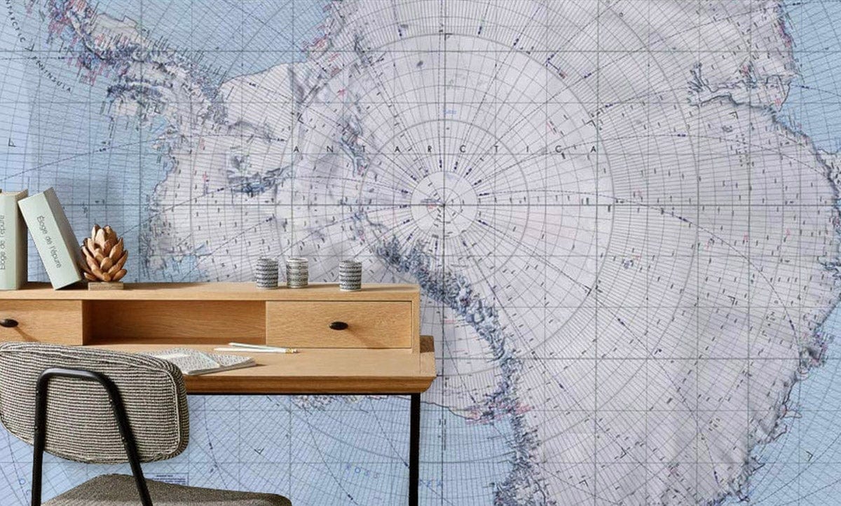 Antarctic Expedition Vintage Map Wallpaper in room with wooden desk, modern chair, subtle blue tones.
