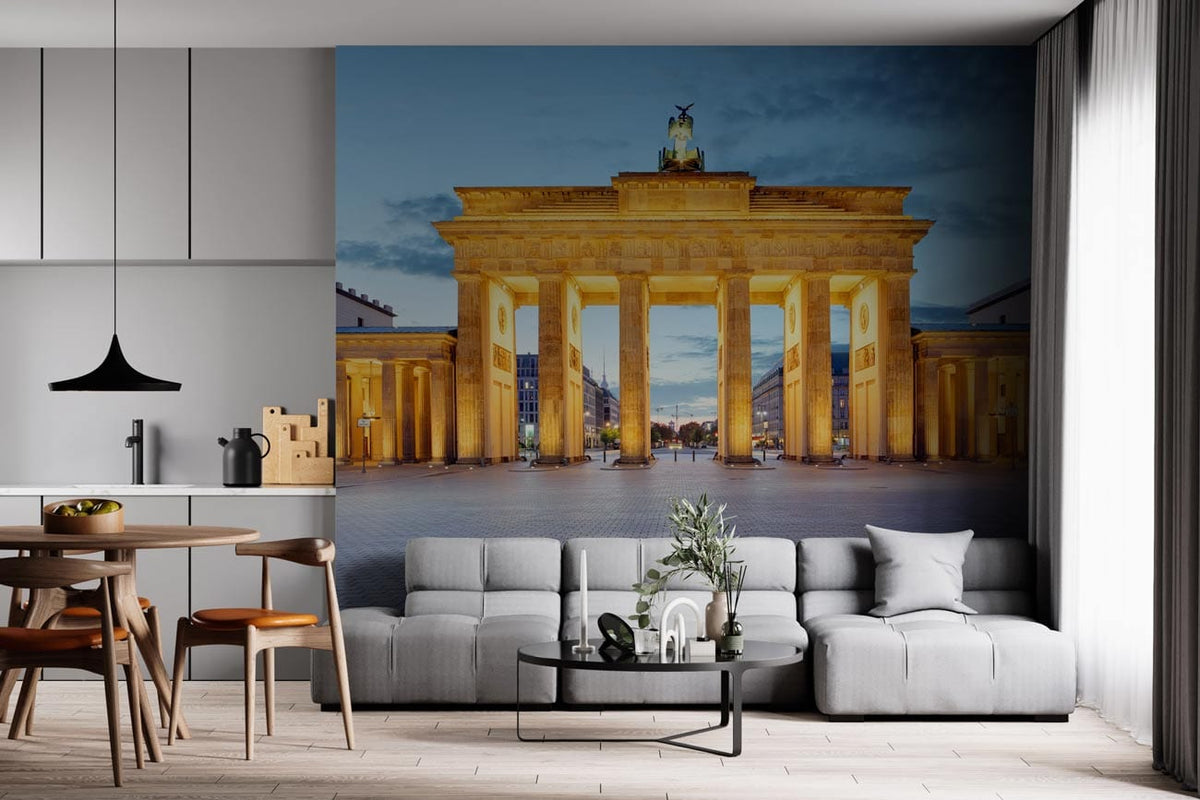 Illuminated Brandenburg Gate mural in modern kitchen-living room; grey sofa, wood flooring, sleek cabinetry.