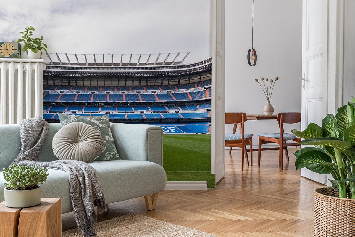 Real Madrid Stadium mural wallpaper in room with light grey sofa, wooden flooring, and modern decor.