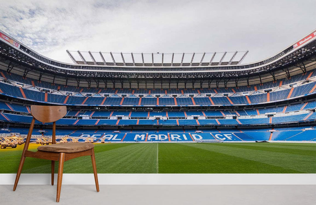 Real Madrid Stadium Mural Wallpaper in a modern room with wooden chair on grey flooring.