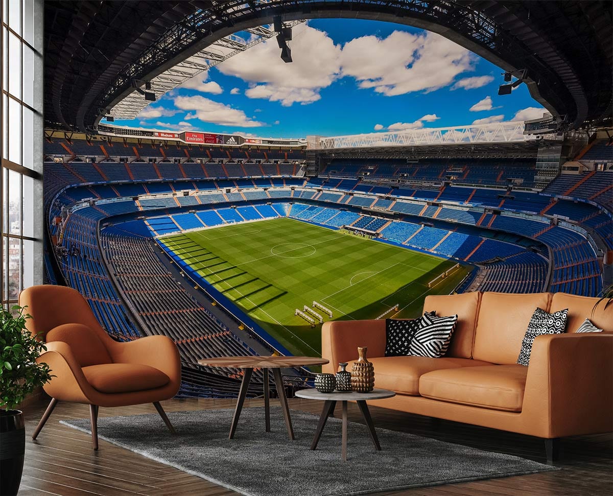 Vibrant football stadium mural wallpaper in living room with tan sofas, wooden flooring, and rug.