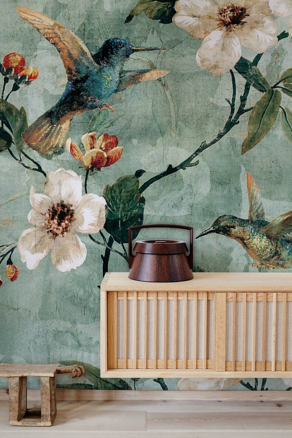 Vintage botanical hummingbird mural wallpaper in soft green with floral design; wooden cabinet, light flooring.
