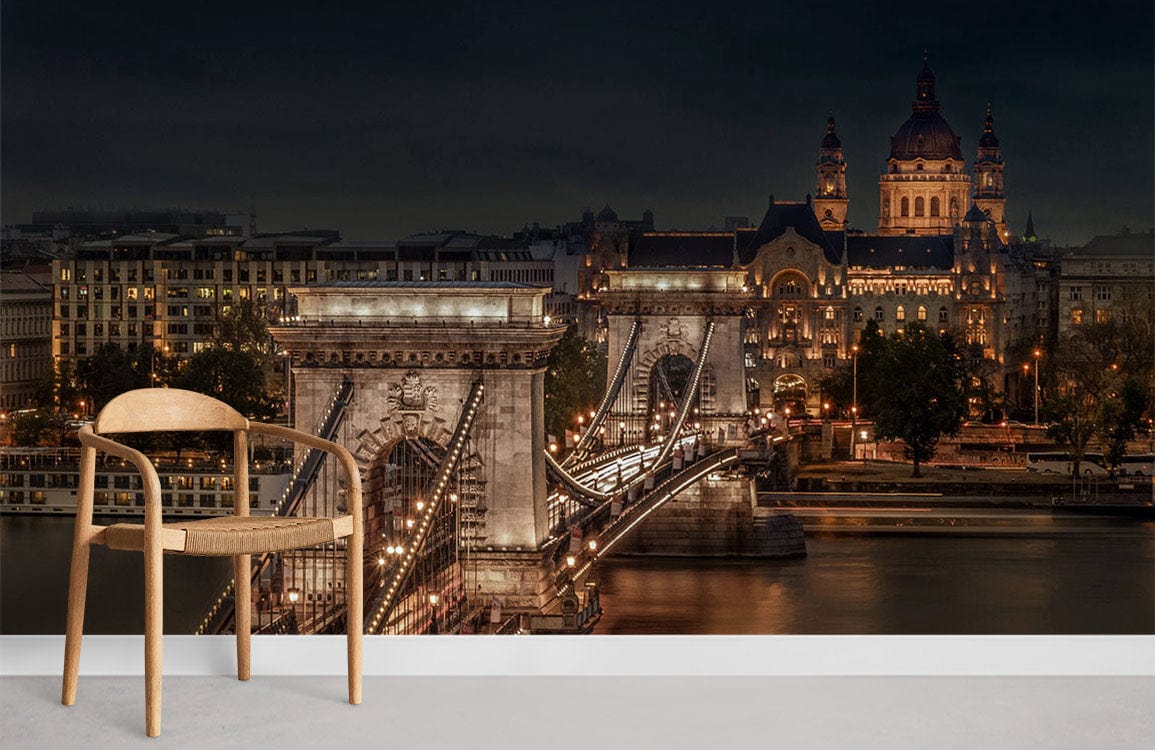 Illuminated cityscape bridge mural wallpaper with wooden chair, grey flooring. Earthy tones enhance decor.