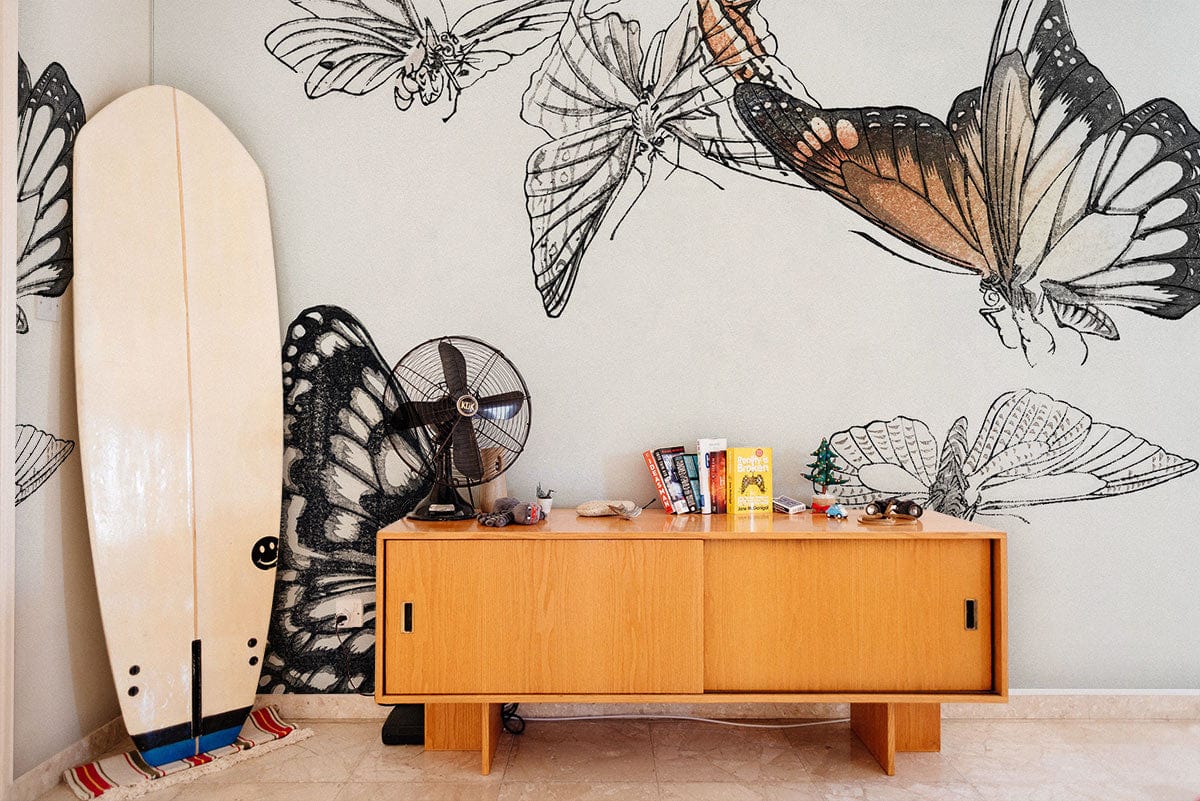 Elegant Butterfly Mural Wallpaper with Mid-Century Sideboard, Surfboard, and Fan in Living Room Setting.