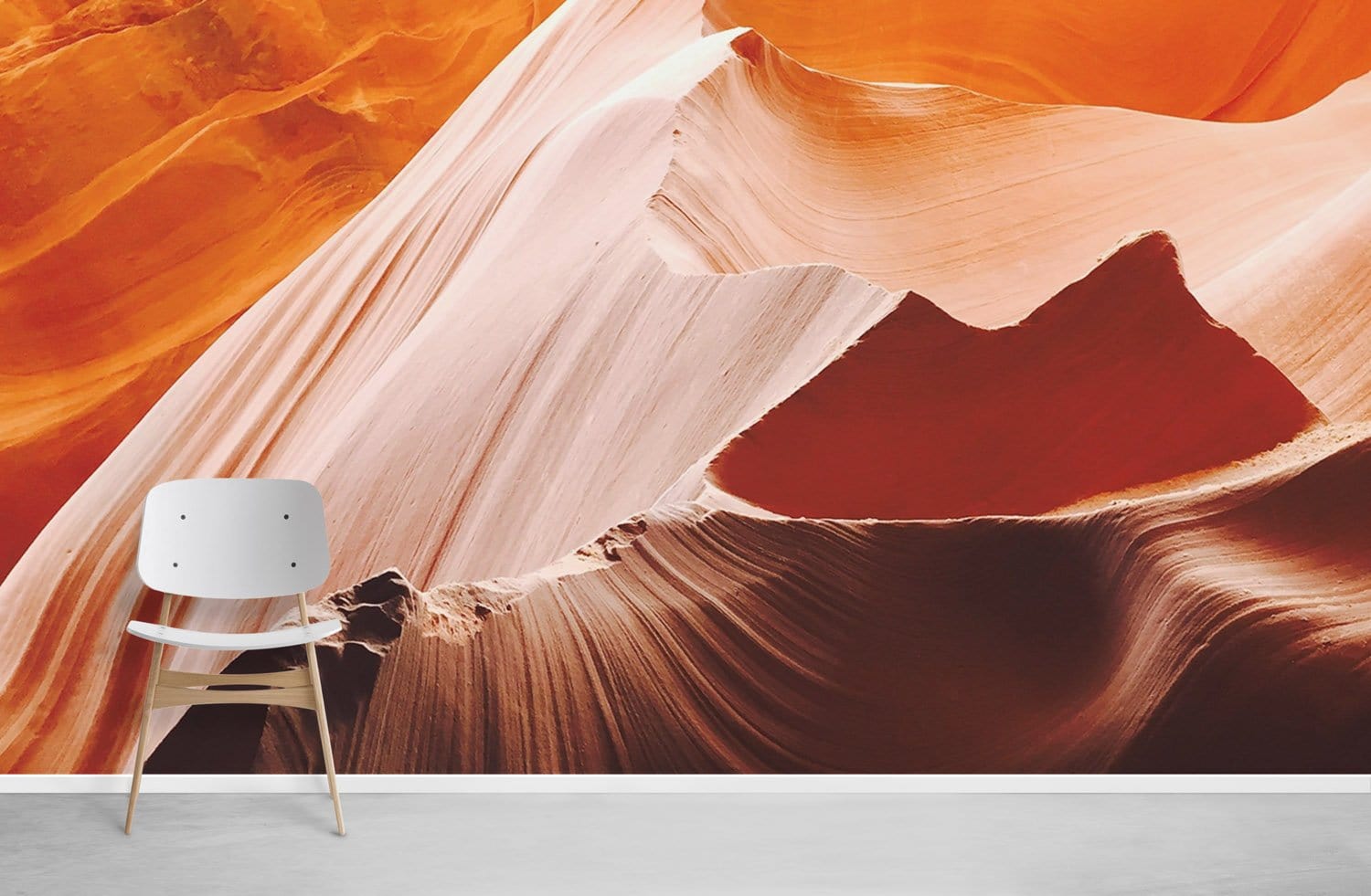 Desert Canyon mural in warm orange earth tones, modern chair, white skirting, concrete flooring.