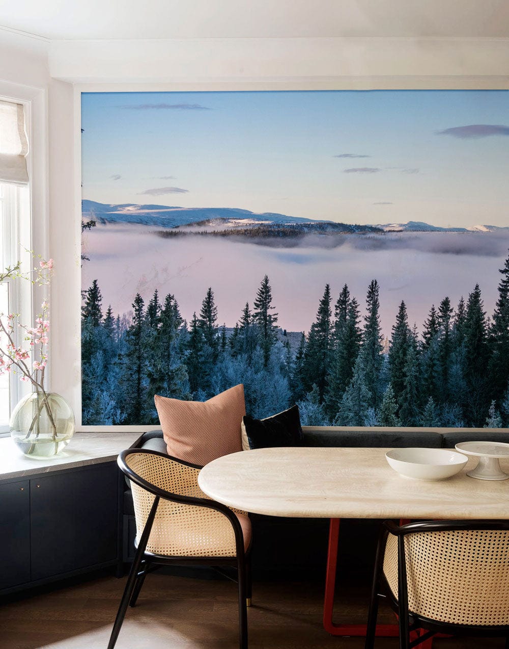 Mist-Covered Forest Mural Wallpaper in dining room with black cabinetry, beige chairs, light wood floor.