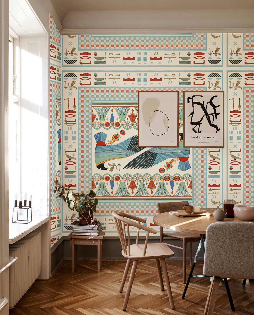 Vintage Egyptian bird wallpaper adds elegance to dining room; wood flooring and modern chairs enhance style.