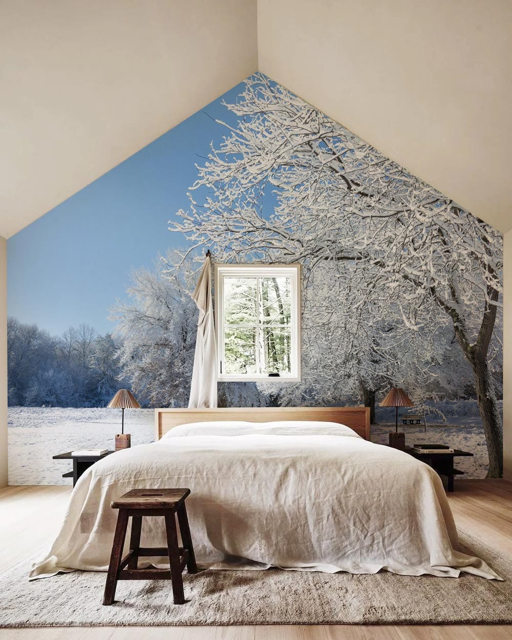 Winter Wonderland mural in bedroom, featuring snowy trees; cosy bed, wooden flooring, beige walls.