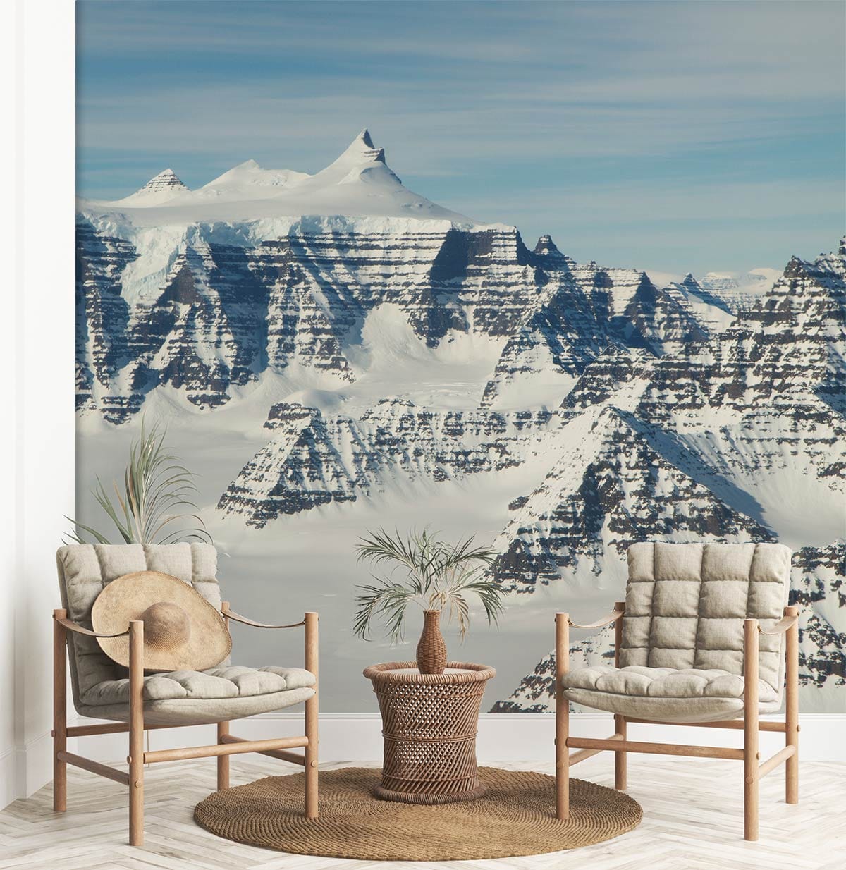 Majestic snow-capped mountain mural with beige chairs, round table, and wooden flooring in lounge setting.
