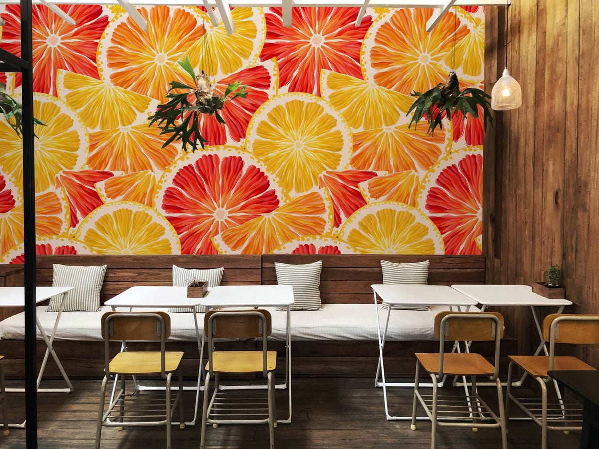 Vibrant Citrus Splash wallpaper with wooden panelling, white tables, metal chairs in modern cafe setting.