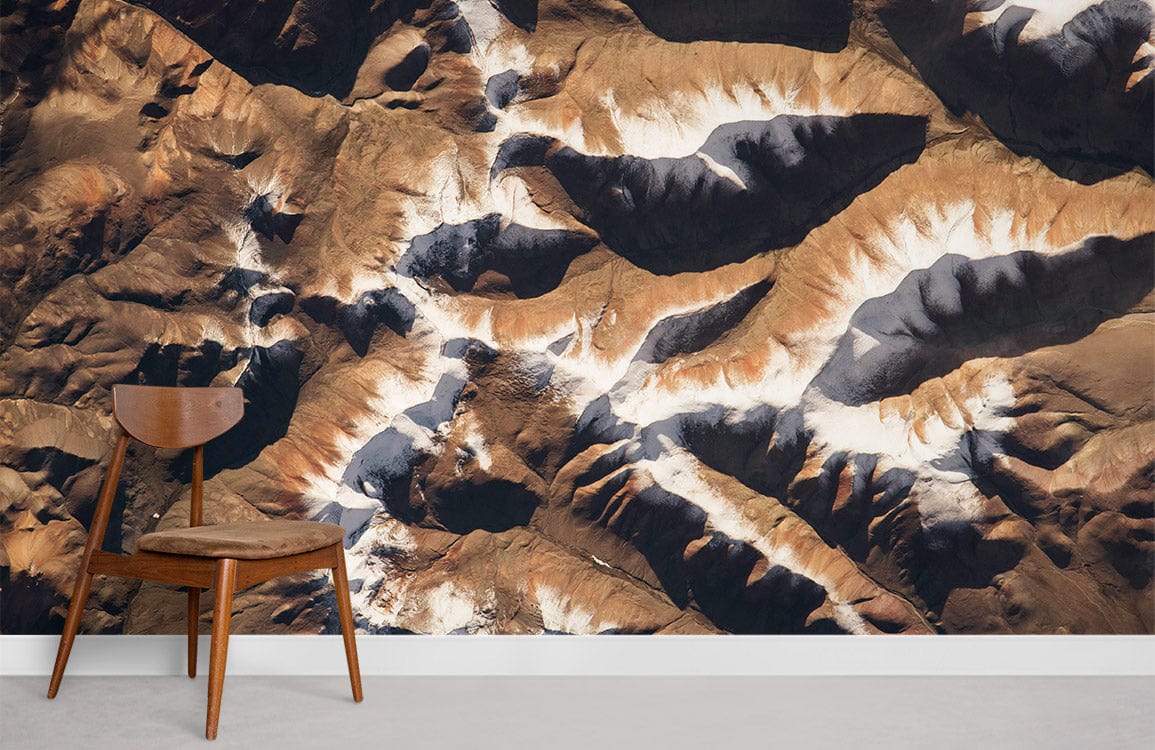 Abstract Earth Tones Geometric Mountainscape Mural Wallpaper, mid-century chair, light grey flooring, modern interior.