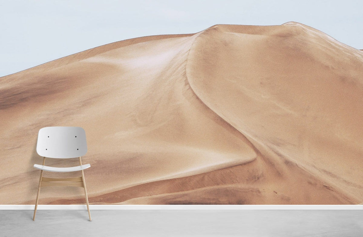 Modern chair against landscape mural wallpaper in earthy tones, featuring natural desert sand dunes.