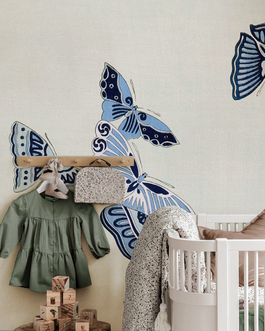 Serene Blue Butterfly Pattern Mural Wallpaper in nursery with white cot and wooden peg rail.