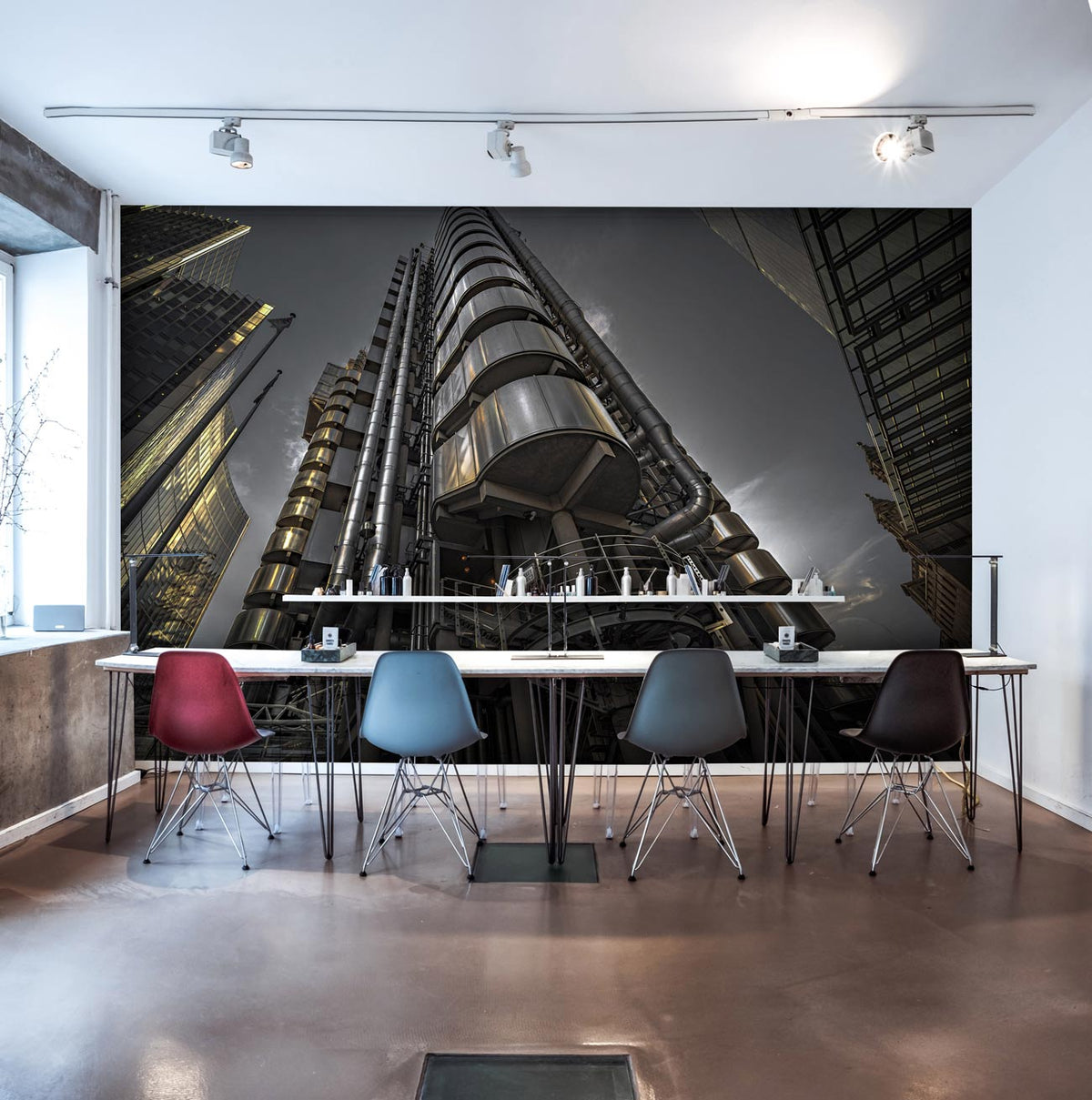 Modern urban skyscraper mural wallpaper; industrial office setting with sleek chairs, polished concrete flooring.