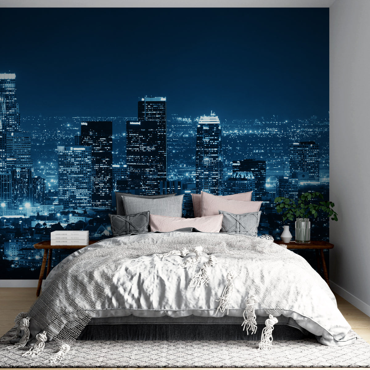 Blue urban night skyline mural wallpaper behind grey bed in modern bedroom with wooden flooring.